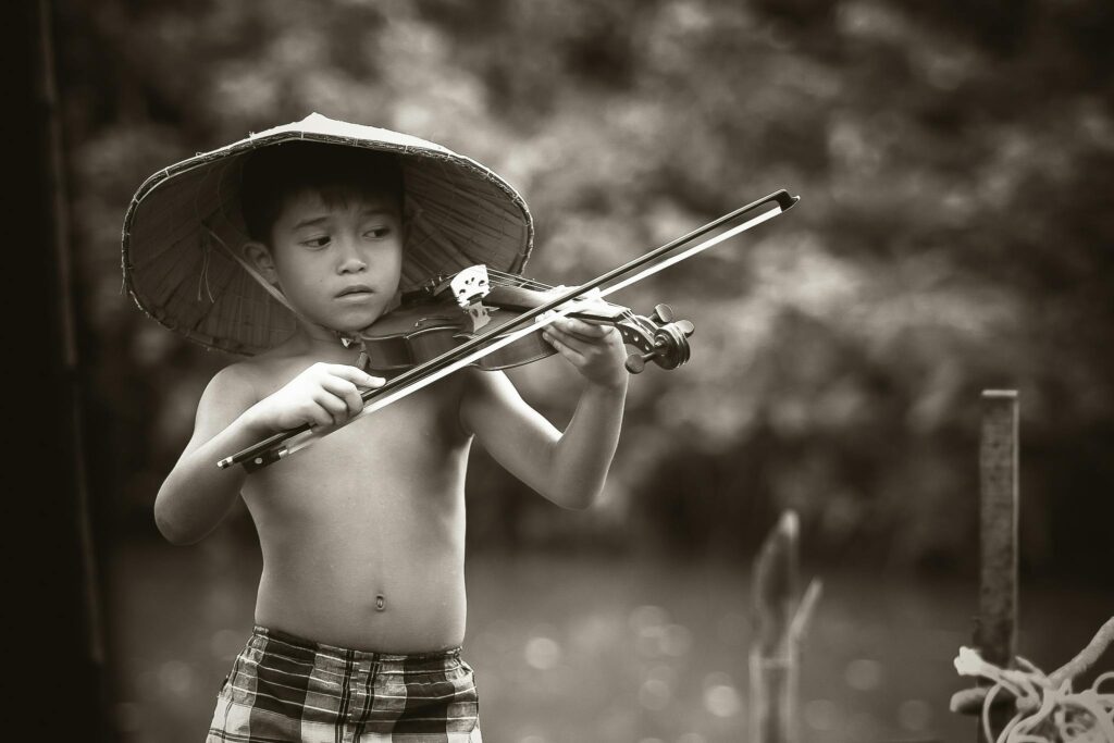 Un enfant apprend à jouer du violon en extérieur, image N&B